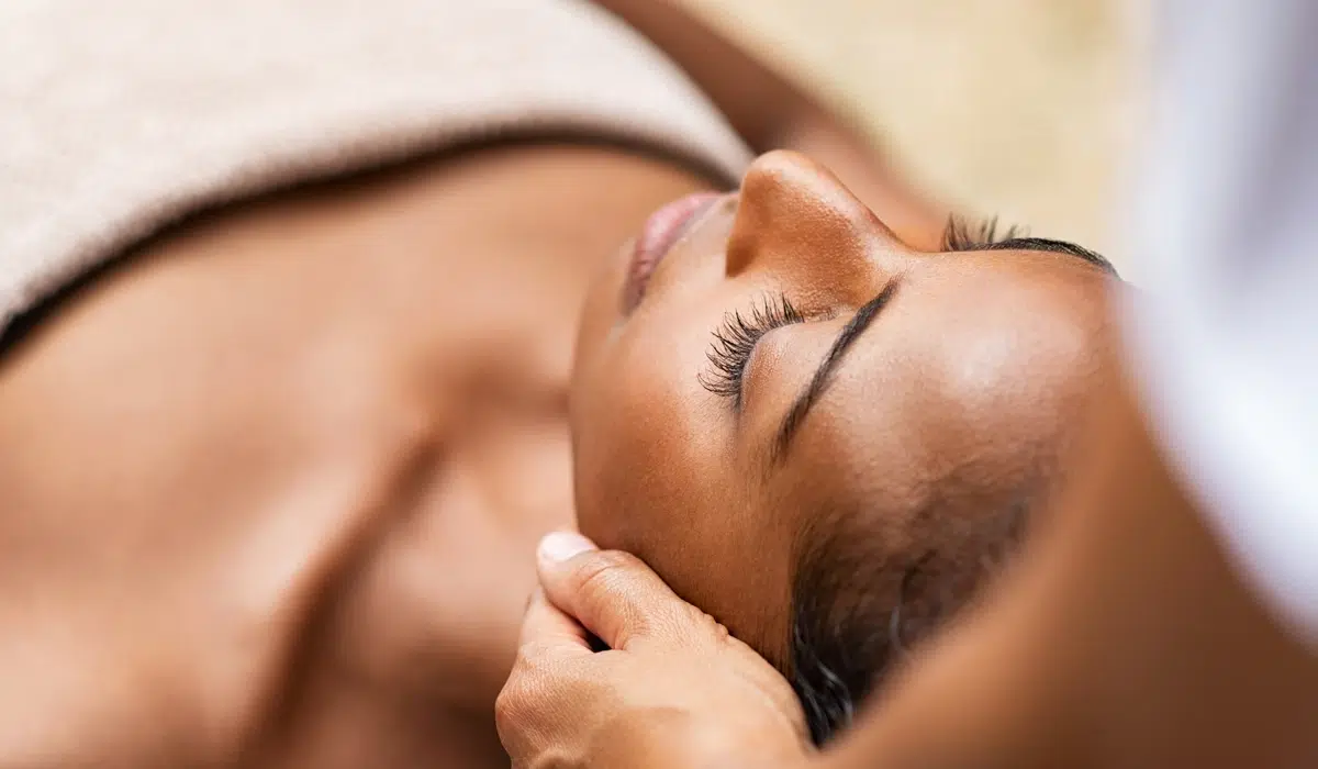 A woman undergoing a professional facial massage, with a focus on relaxation and skincare in a tranquil setting