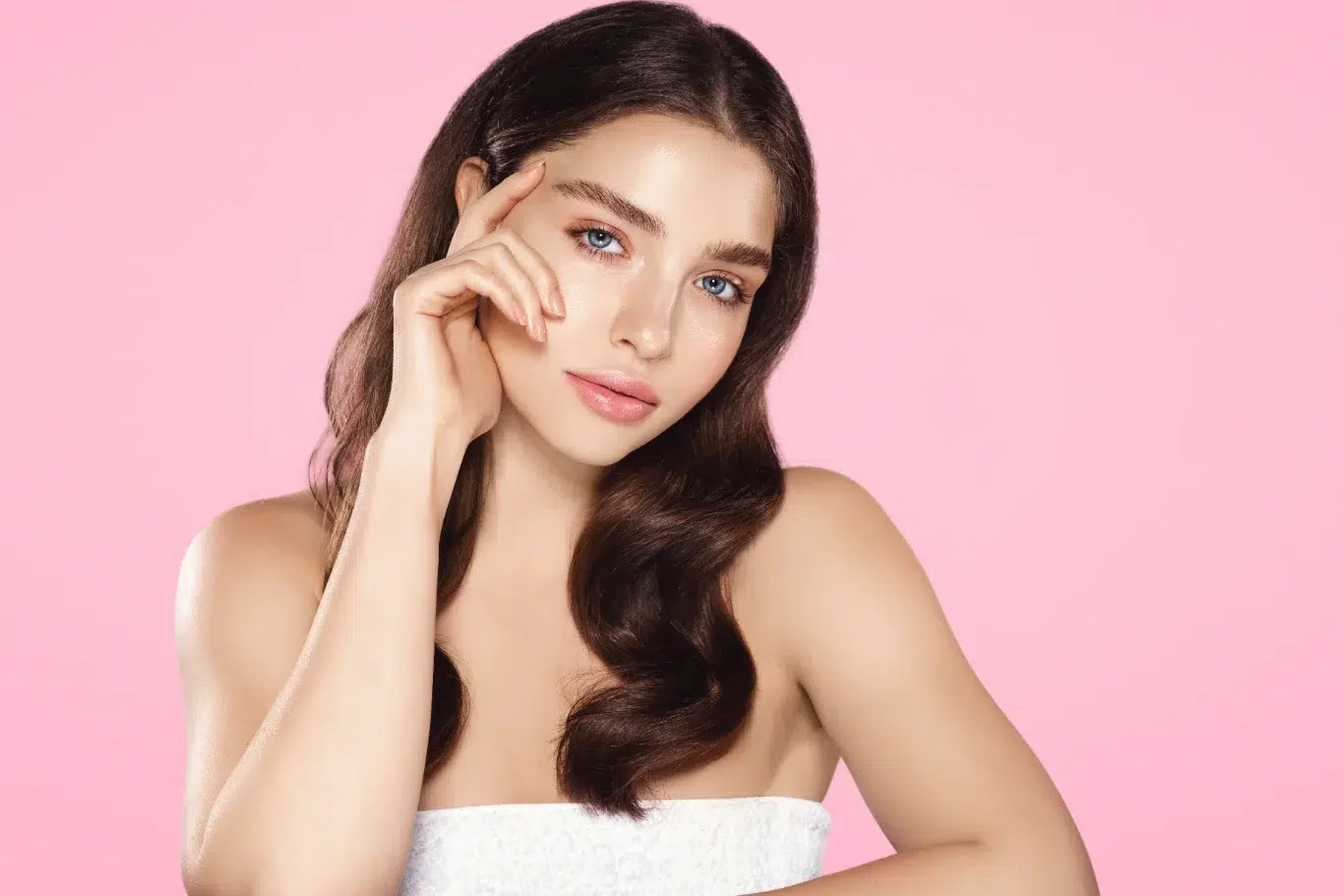 A beauty portrait of a young woman with wavy brunette hair and radiant skin